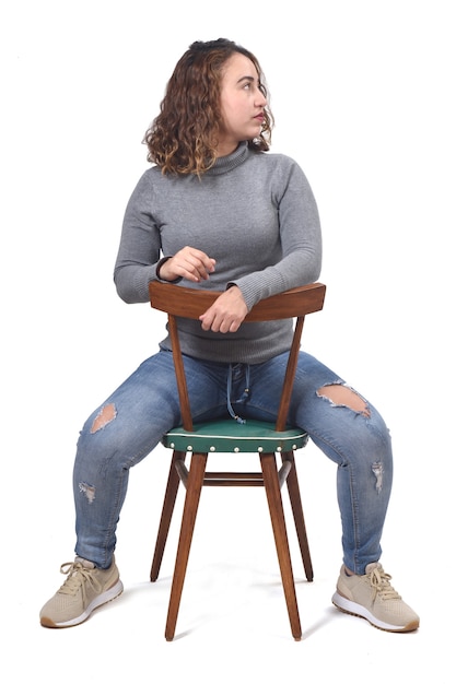 Portret kobiety siedzącej na krześle w białej przestrzeni, widok z tyłu krzesła i wygląd z boku