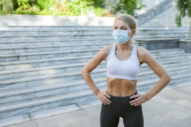 Portret kobiety slim fit w masce medycznej na zewnątrz. Sport w okresie covid-19