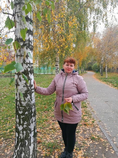 Zdjęcie portret kobiety stojącej przy drzewie jesienią