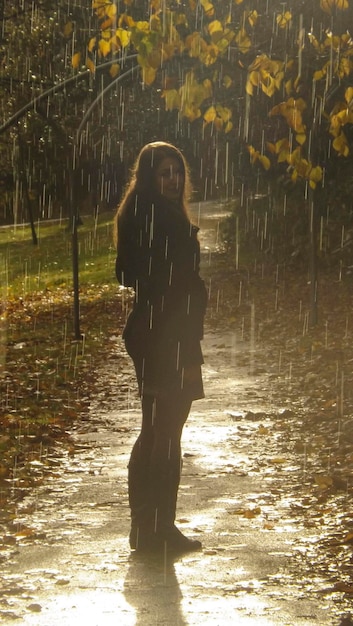Portret kobiety stojącej w deszczu na chodniku