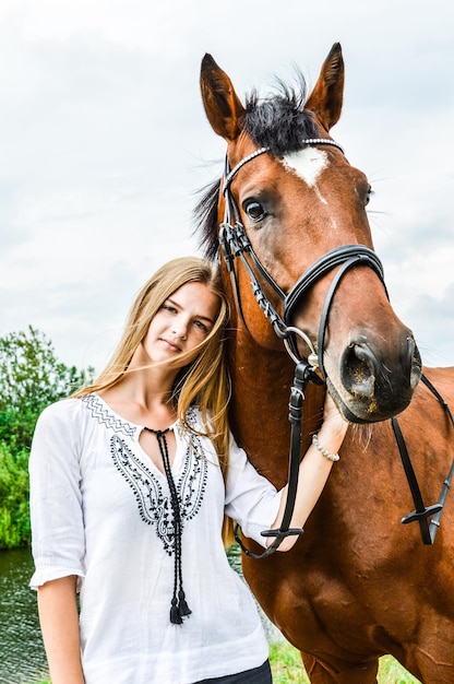 Zdjęcie portret kobiety stojącej z koniem na tle nieba