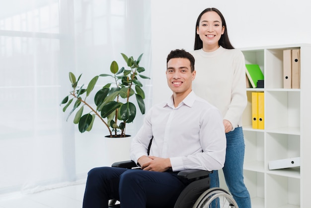Zdjęcie portret kobiety stojącej za uśmiechniętym biznesmenem siedzi na wózku inwalidzkim