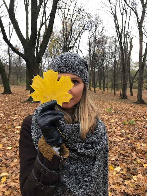 Zdjęcie portret kobiety trzymającej liść klonu jesienią w lesie