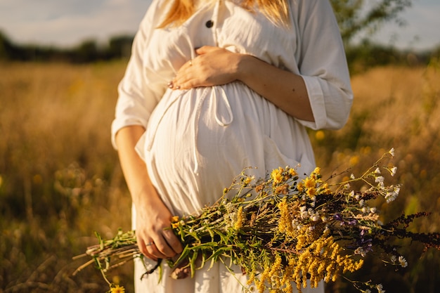 Zdjęcie portret kobiety w ciąży piękna młoda kobieta w ciąży w białej sukni spaceruje po polu