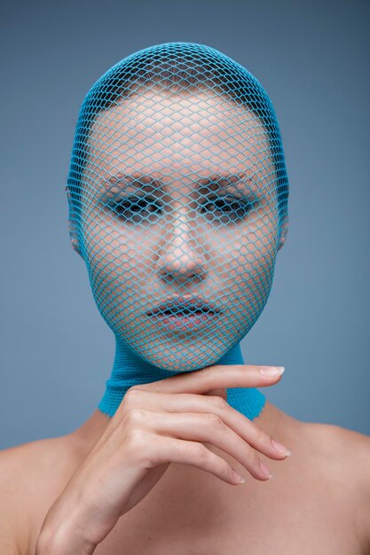 Portret kobiety z niebieskimi pończochami na głowie na niebieskim tle. Moda uroda portret