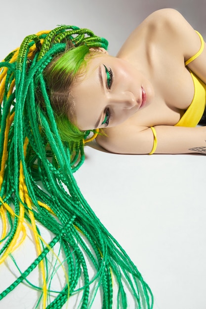 Portret kobiety z twórczo farbowanymi włosami w kolorze zielono-żółtym.