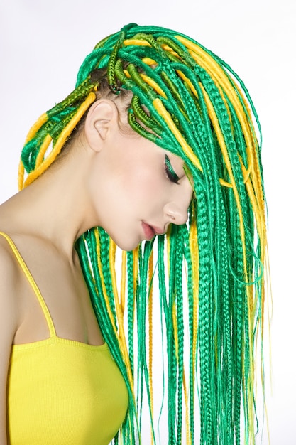 Portret kobiety z twórczo ufarbowanymi włosami w kolorze zielonym i żółtym. Kolorowe jasne dredy, piękny nowoczesny makijaż