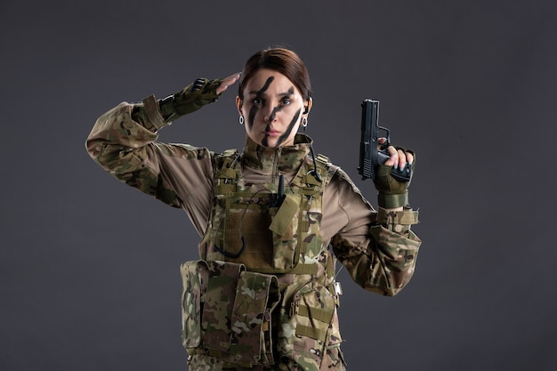 Portret kobiety żołnierza w kamuflażu z ciemną ścianą pistoletu
