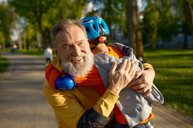 Portret kochającego dziadka i wnuka przytulających się po jeździe na rolkach