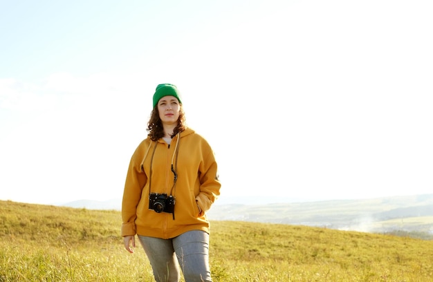 Portret kręcone kobieta fotograf na zewnątrz. Kobieta chodzi i robi zdjęcia swoim aparatem