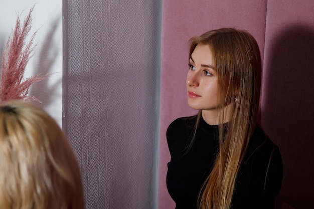Portret ładna blondynka młoda kobieta w pokoju, siedząc i patrząc daleko. Koncepcja słuchania mówcy lub oglądania konferencji