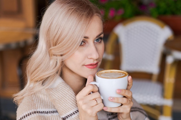 Portret ładna blondynka uśmiechnięta kobieta w przytulnej kratce siedzi w kawiarni