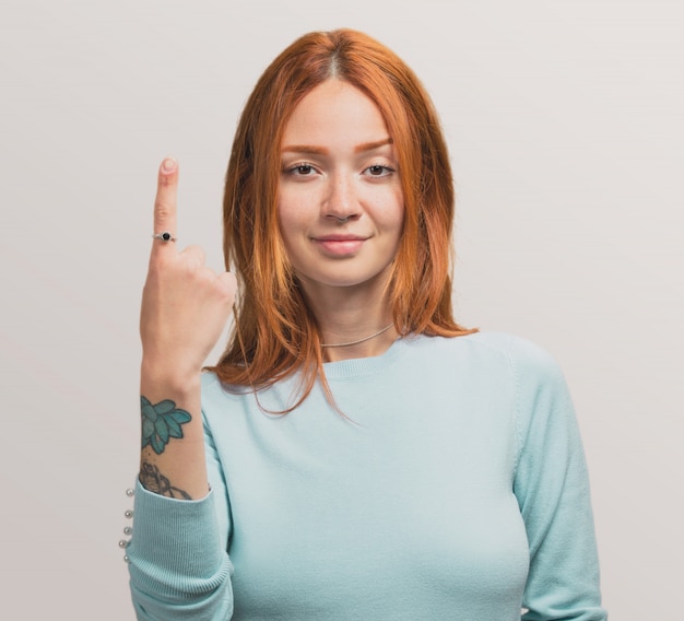 Portret ładna rudzielec dziewczyna robi numerowi jeden gest