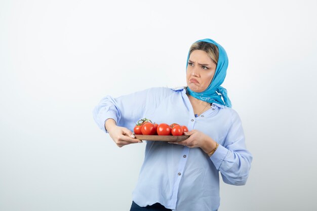 Portret ładne kobiety w niebieskim szalem trzymając deskę z czerwonych pomidorów