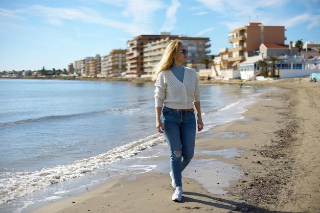 Portret ładnej kobiety spacerującej po plaży miejskiej na tle morza