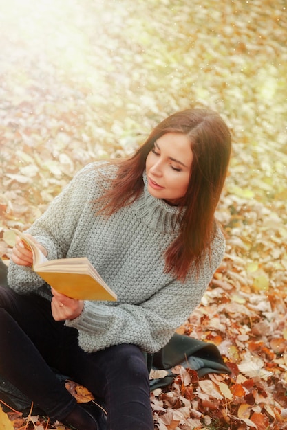 Portret ładnej młodej kobiety w przypadkowej odzieży w jesiennej czytelniczej książce