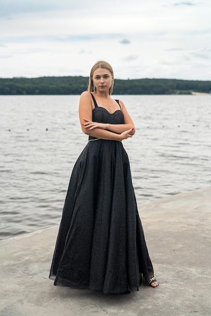 Portret ładnej pani w modnej ciemnej sukience w pobliżu stawu