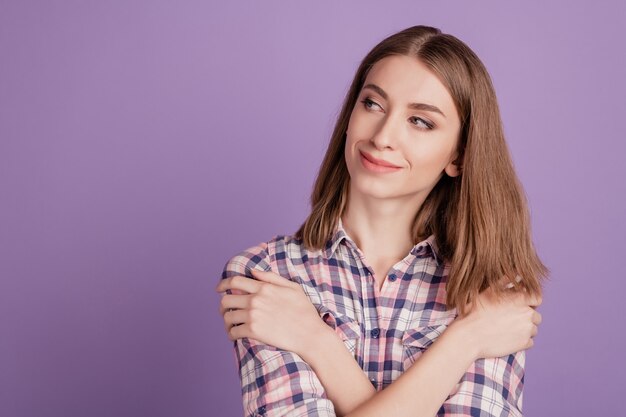 Portret ładnie wyglądającej słodkiej uroczej dziewczyny przytulającej się, wyglądającej na pustą przestrzeń odizolowaną na fioletowym tle