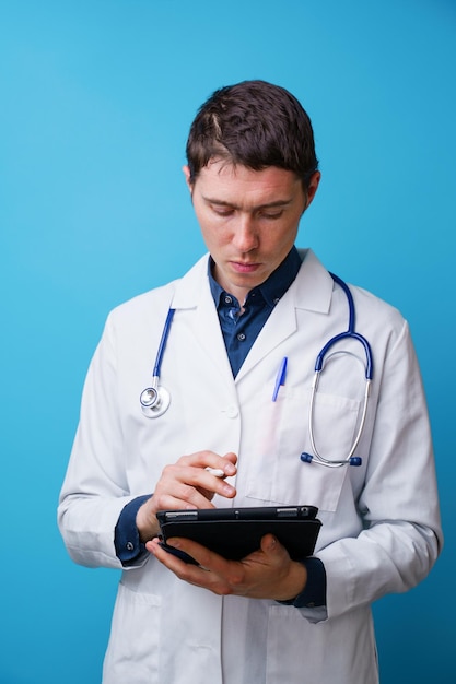 Portret lekarza ze stetoskopem i tabletem w ręku na niebieskim tle