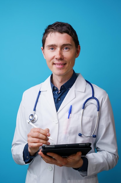 Portret lekarza ze stetoskopem i tabletem w ręku na niebieskim tle