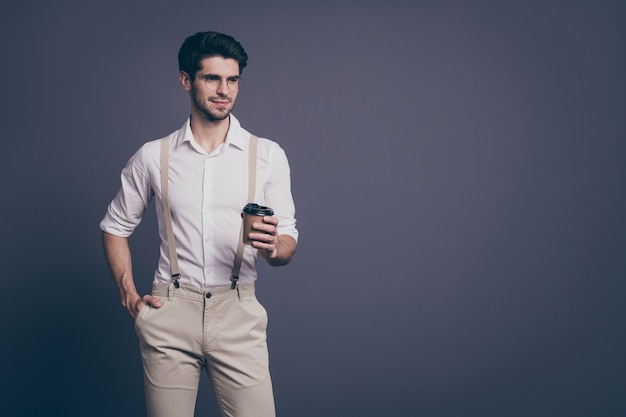 portret macho odnoszącego sukcesy biznesmena lidera pijącego gorącą kawę na wynos ubrany formalny koszula beżowe szelki spodnie specs.