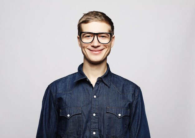 Portret mądrego młodego mężczyzny noszącego okulary stojącego na białym tle