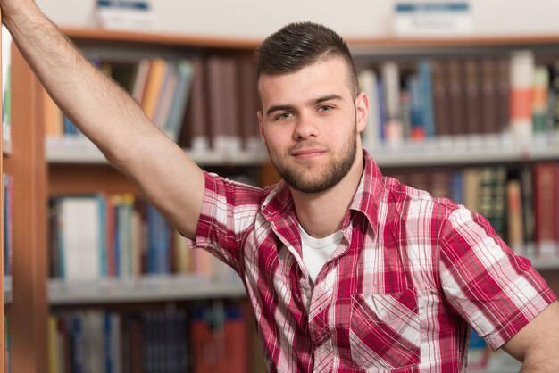 Portret mądrego studenta rasy kaukaskiej w bibliotece kolegium. Płytkiej głębi ostrości