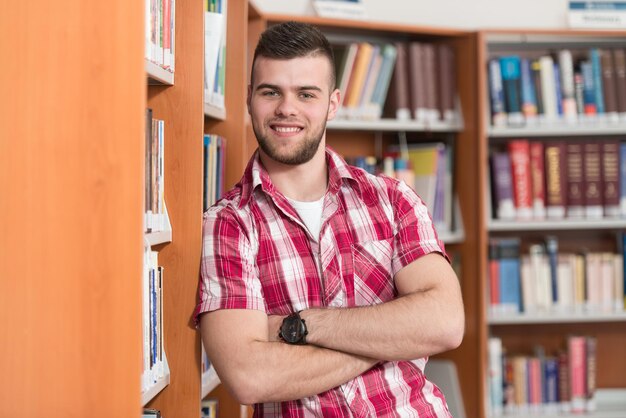 Portret mądrego studenta rasy kaukaskiej w bibliotece kolegium. Płytkiej głębi ostrości