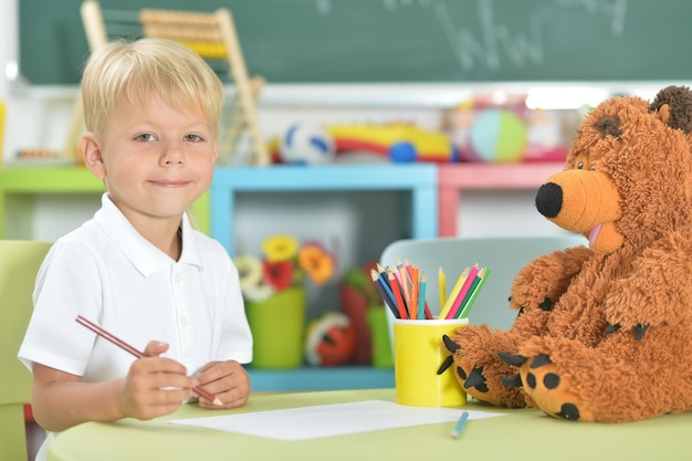 Portret małego chłopca rysującego ołówkiem w klasie