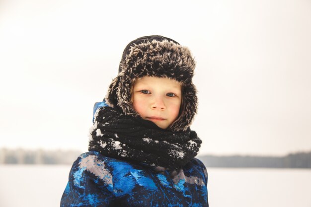 Portret małego chłopca w kapeluszu zimą w parku