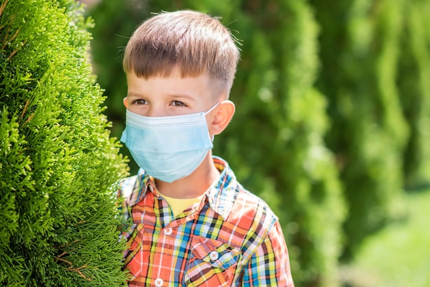 Portret małego chłopca w masce ochronnej na ulicy podczas pandemii koronawirusa i Covid - 19