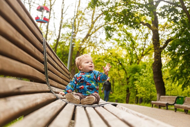 portret małego chłopca w parku na ławce łapania baniek mydlanych zbliżenie