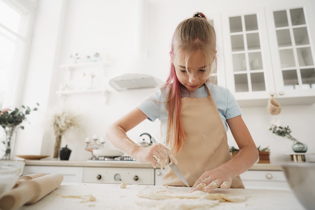 Portret małej blond nastolatki noszącej fartuch w kuchni