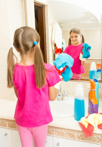 Portret małej dziewczynki do polerowania lustra w łazience ze środkiem czyszczącym