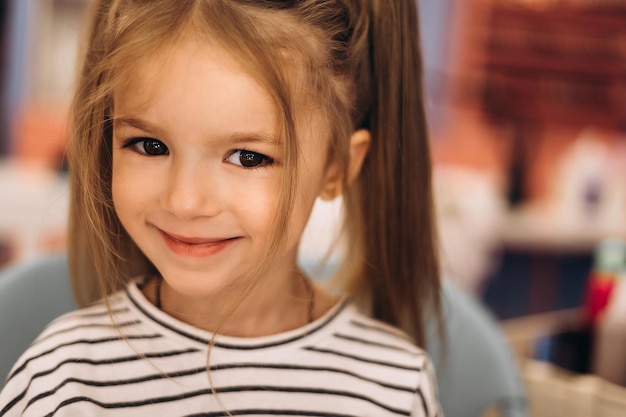 Portret małej pięknej dziewczynki ze stylową fryzurą w salonie kosmetycznym wyrażający szczęście ładnego dzieciaka