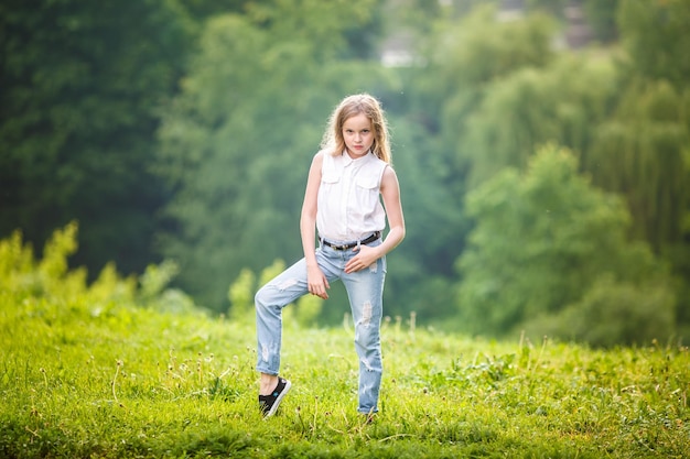 Portret małej pięknej stylowej dziewczynki na zielonym tle lasu