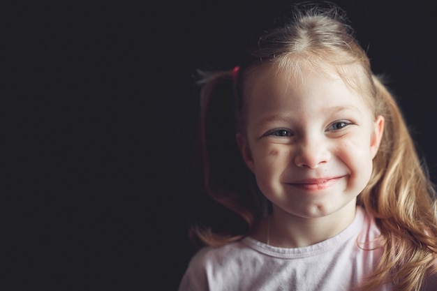 portret małej wesołej dziewczyny na czarnym tle