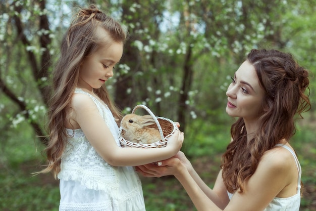 Portret matki i córki w lesie W rękach dziewczynki kosz z królikiem