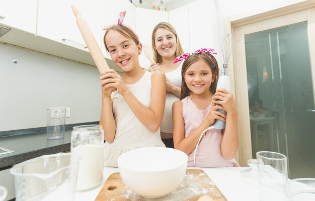 Portret matki i dwóch córek pozujących w kuchni podczas gotowania
