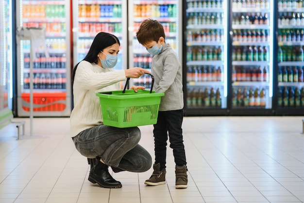 Portret Matki I Jej Synka Noszących Ochronną Maskę Na Twarz W Supermarkecie Podczas Epidemii Koronawirusa Lub Wybuchu Grypy. Puste Miejsce Na Tekst.