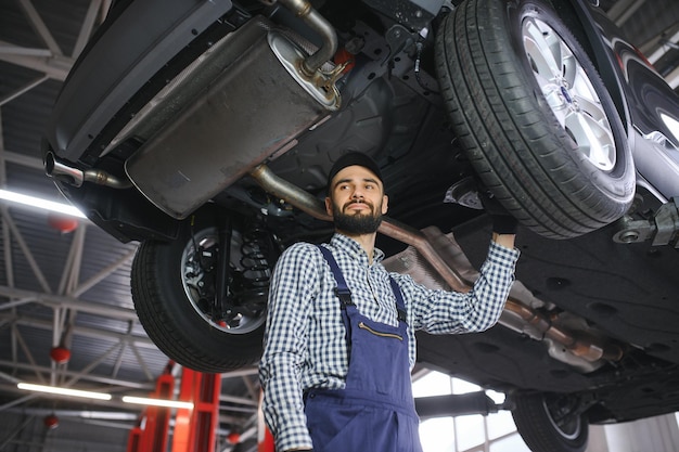 Portret mechanika naprawiającego podniesiony samochód