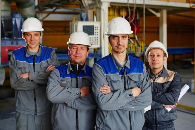 Portret męskich pracowników fabryki w pokoju na tle sprzętu