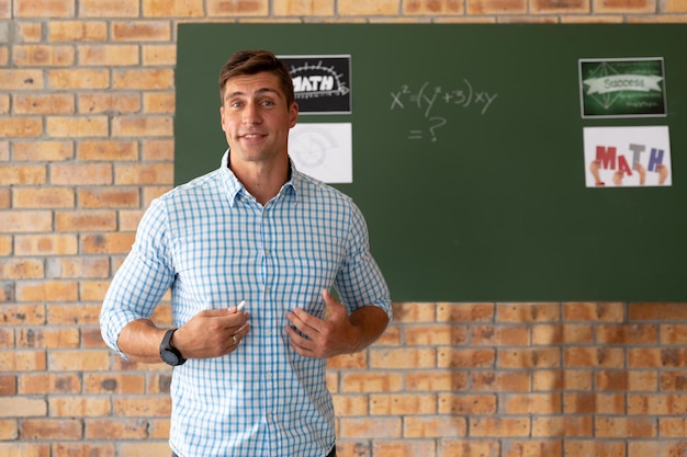 Portret męskiego kaukaskiego nauczyciela nauczania matematyki w klasie w szkole