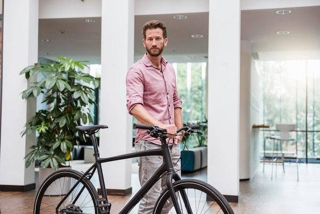 Portret mężczyzna z bicyklem w biurze