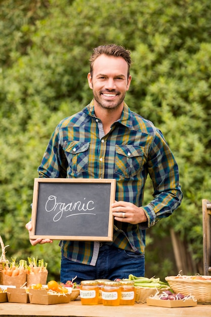 Zdjęcie portret mężczyzna z blackboard sprzedawania warzywami