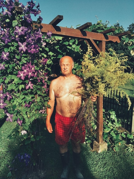 Zdjęcie portret mężczyzny bez koszuli stojącego przy roślinach