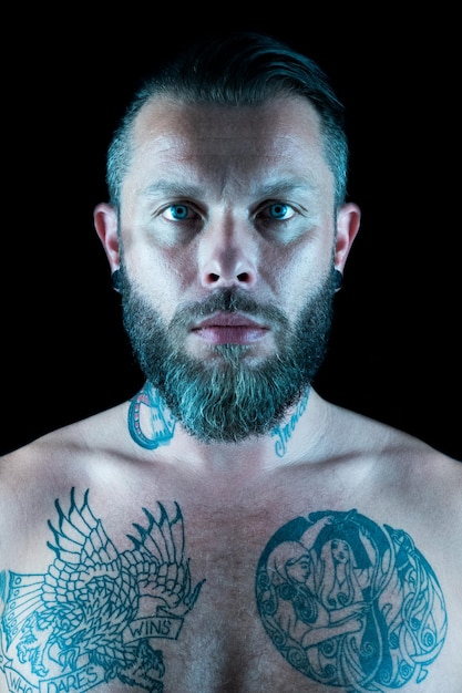 Zdjęcie portret mężczyzny bez koszuli z tatuażem na czarnym tle
