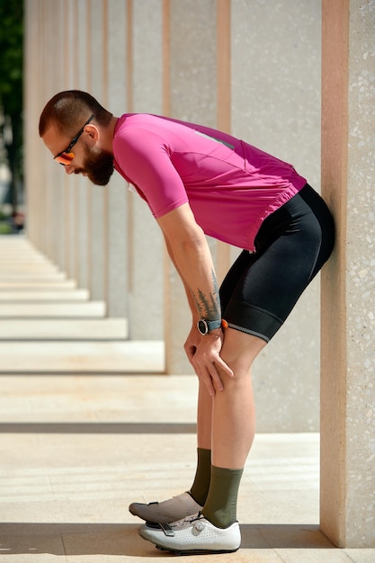 Portret mężczyzny biegacza odpocząć po joggingu, stojąc między kolumnami, skopiuj przestrzeń dla wiadomości tekstowej, sportowiec robi sobie przerwę