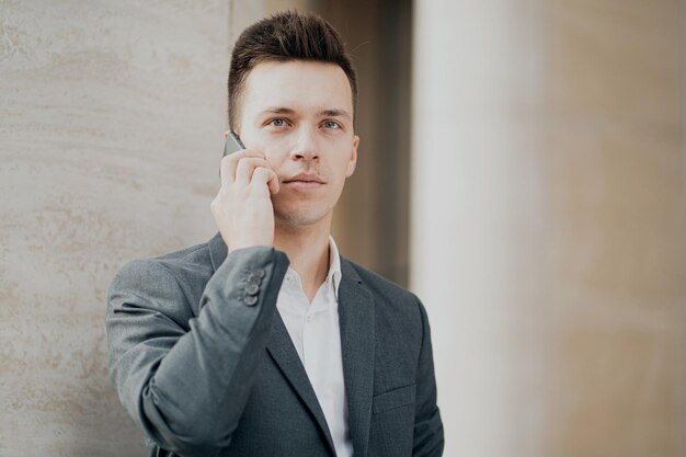 Portret mężczyzny, biznesmena trzymającego nowy telefon, z którym partner chce porozmawiać o pracy
