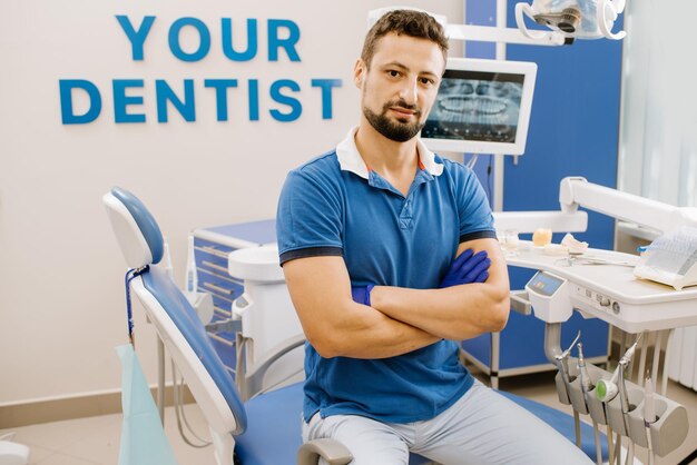 Portret mężczyzny dentysty siedzącego przy swoim sprzęcie dentystycznym w pomieszczeniu